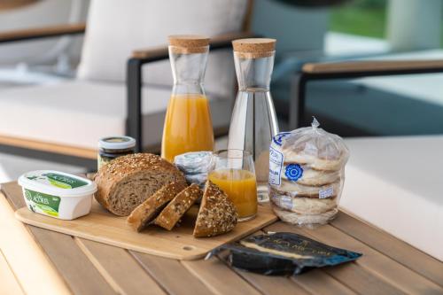 a wooden tray with bread and orange juice and a bottle at Auréa House - Luxury Ocean View in Feteiras