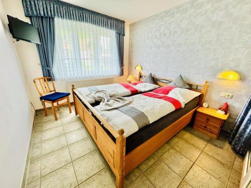 Un dormitorio con una cama de madera con una silla y una ventana. en Haus Vier Freunde, Vincent, en Warnemünde