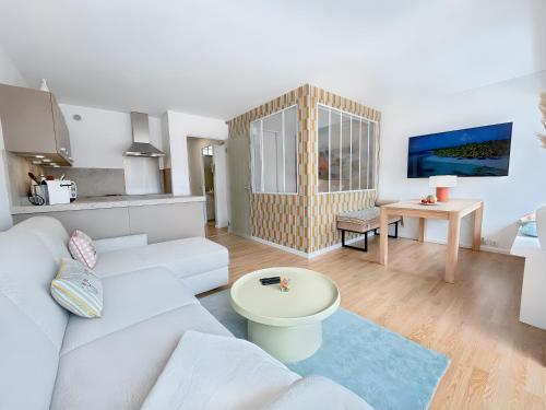 un salon avec un canapé blanc et une table dans l'établissement Charmant Appartement au Cœur de Deauville avec Balcon et plage à 10 min à Pied, à Deauville