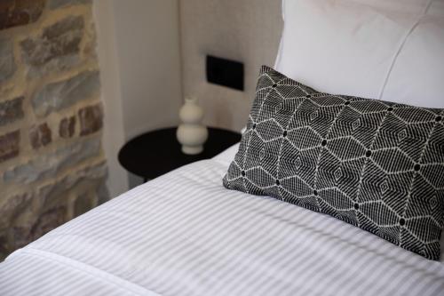 a bed with a black and white pillow on it at Stitch&Stone Suites in Gjirokastër