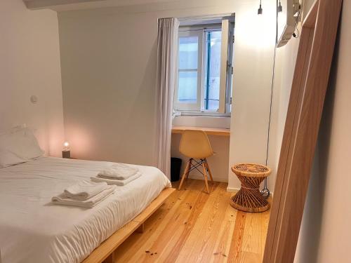a bedroom with a bed with a window and a chair at Loureiro 59 in Coimbra