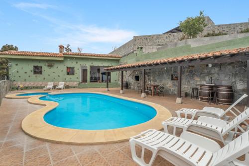 a swimming pool with chairs and a house at Casa Rural Tijoco in Adeje