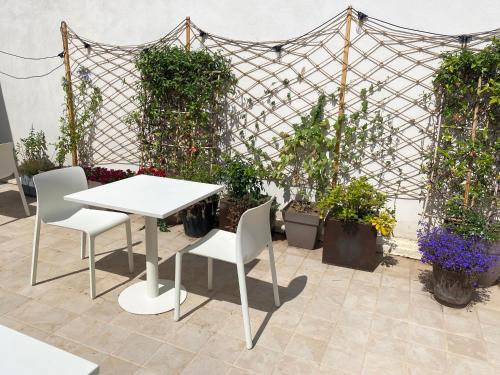 a white table and chairs in a garden with plants at La Hugotine in Marseillan