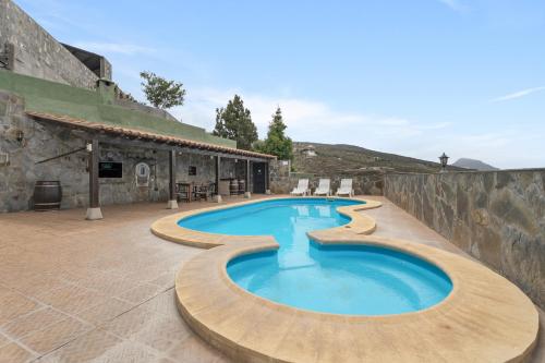 a swimming pool in front of a stone building at Casa Rural Tijoco in Adeje