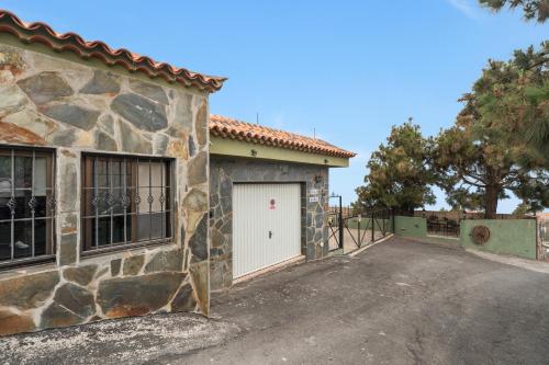 a stone house with a white garage door at Casa Rural Tijoco in Adeje