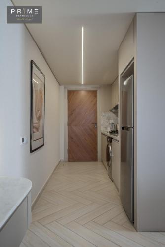 a hallway with a wooden door and a kitchen at Prime Residence Sheikh Zayed in Sheikh Zayed
