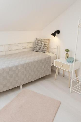 a white bedroom with a bed and a table at xgeschlossen in Hirschaid