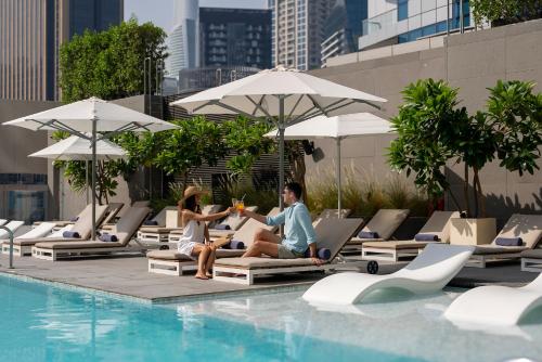 two people sitting on lounge chairs next to a swimming pool at InterContinental Dubai Marina by IHG in Dubai
