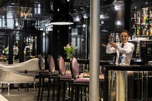 a man standing at a bar holding a glass at Maison Albar - Le Diamond in Paris