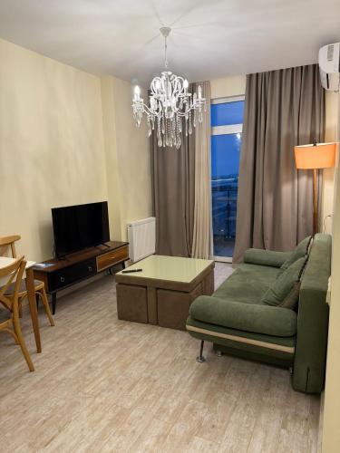 a living room with a green couch and a chandelier at Apartamenti v Batumi in Batumi