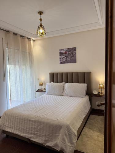 a bedroom with a large bed with white sheets and a chandelier at Dar Dina Havre de paix sous les cèdres d'Ifrane in Ifrane