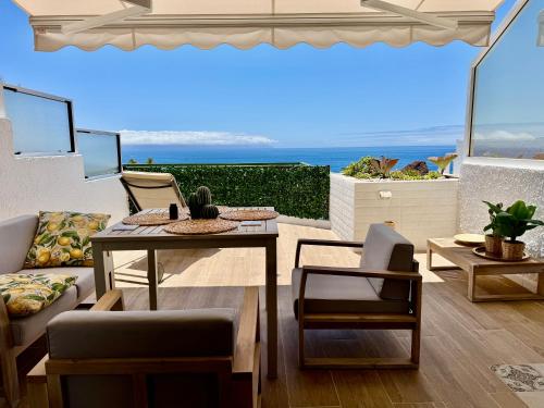 eine Terrasse mit Tisch und Stühlen und dem Meer in der Unterkunft Casa Oceanico Los Gigantes in Acantilado de los Gigantes