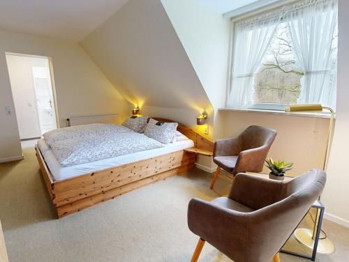 a bedroom with a bed and two chairs in front of a window at Reiterpension Marlie in Scharbeutz