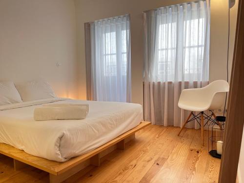 a bedroom with a white bed and a white chair at Loureiro 59 in Coimbra
