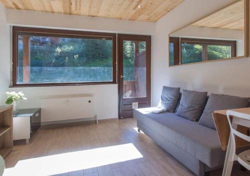 a living room with a couch and some windows at Résidence Le Relax - Megève Centre in Megève