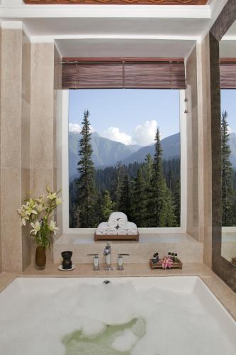 a bath tub in a bathroom with a large window at The Khyber Himalayan Resort & Spa in Gulmarg