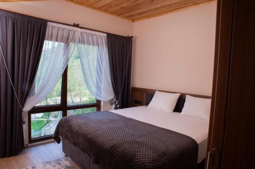 a bedroom with a bed and a large window at Alnada Resort in Düzköy