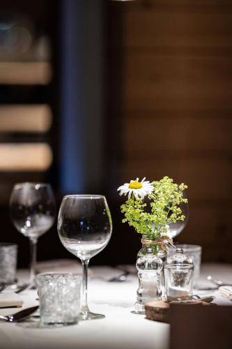 a table with wine glasses and a vase with a flower in it at Hotel Anewandter in Brunico
