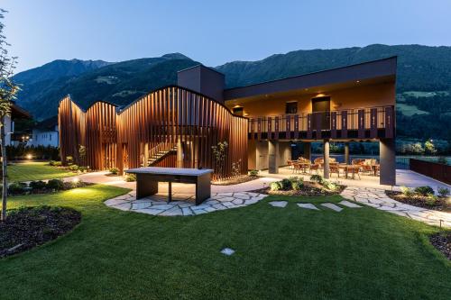 a house with a bench in the middle of a yard at Hotel Anewandter in Brunico