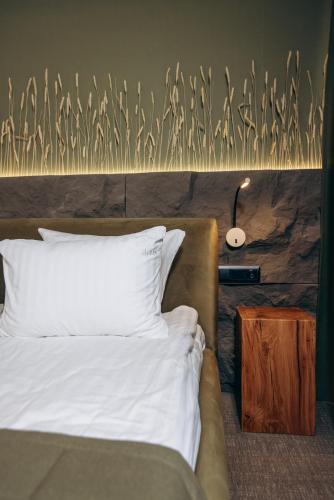 a bedroom with a bed with white sheets and a lamp at GasthauS & SPA in Bukovel