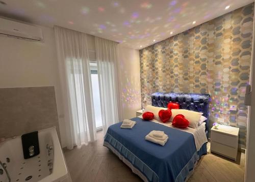 a bedroom with a blue bed with red pillows and a tub at Suite Eleven in Naples