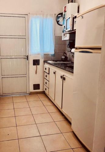 a kitchen with a white refrigerator and a tile floor at Aguasanas casas termales Chajari in Chajarí