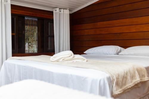 two beds in a room with white sheets and pillows at Pousada Do Sol Ilha do Mel in Paranaguá