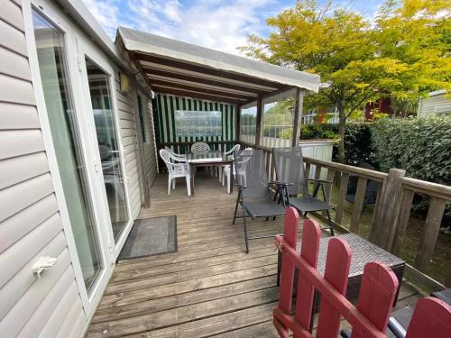 eine Holzterrasse mit einem Tisch und Stühlen darauf in der Unterkunft Bungalow Confort Gastes Jacuzzi in Gastes