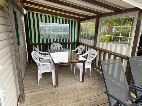 eine Holzterrasse mit einem Tisch und Stühlen darauf in der Unterkunft Bungalow Confort Gastes Jacuzzi in Gastes