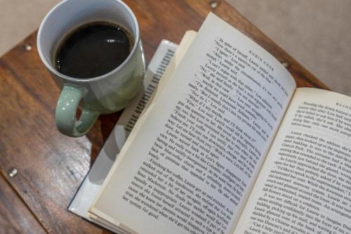 an open book with a cup of coffee on a table at Free Parking - Central - Sleeps 6 - 2 Bedrooms in East Calder