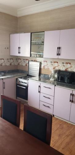 a kitchen with white cabinets and a stove and a table at Yaa Asantewaa Inn in Ejisu