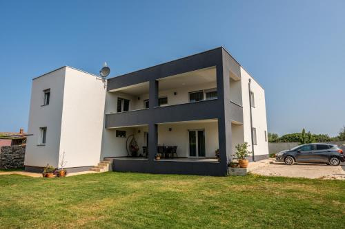 a white house with a car parked in a yard at Holiday home Galižana in Galižana