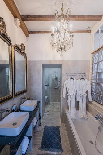 La salle de bains est pourvue de 2 lavabos, d'une baignoire et d'un lustre. dans l'établissement Gîte de l'Antiquaire au cœur de la Citadelle Blaye, à Blaye