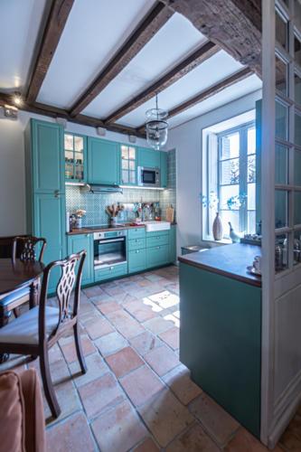 une cuisine avec des armoires bleues et une table et des chaises dans l'établissement Gîte de l'Antiquaire au cœur de la Citadelle Blaye, à Blaye