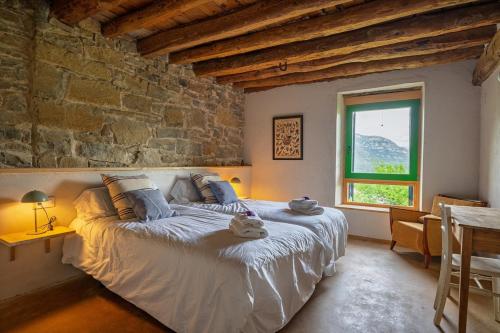 a bedroom with a large bed with a stone wall at Borda Viñuels in Planillo
