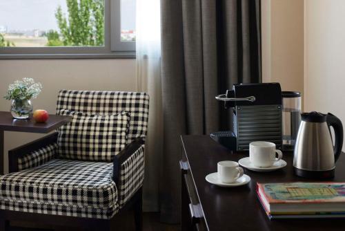 a living room with a chair and a table with a coffee maker at NH Alcorcón in Alcorcón