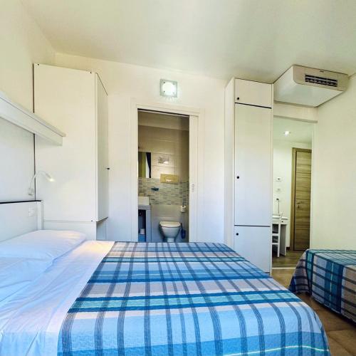 a bedroom with a blue and white bed and a bathroom at Hotel Ondina in Lido di Jesolo