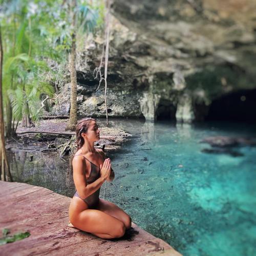 a woman sitting on a rock in front of a pool of water at Portal Xibalba in Playa del Carmen