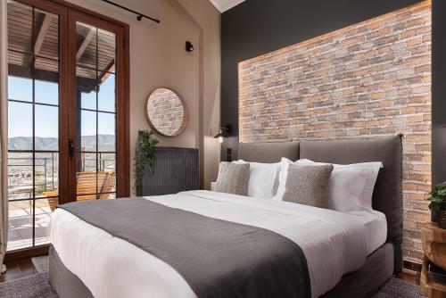 a bedroom with a large bed and a brick wall at Tilemachos by GM Luxury Suites Kalavryta in Kalavrita