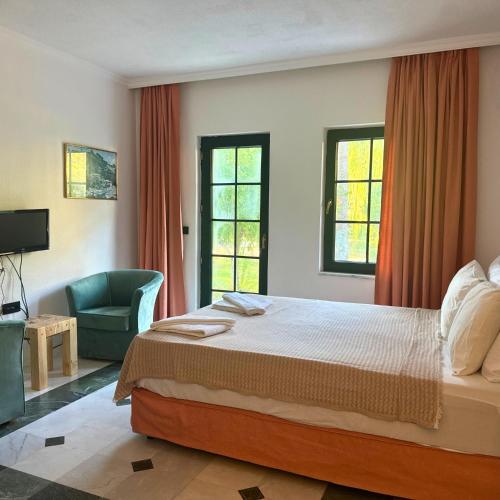 a bedroom with a bed and a chair and windows at Club Mel Holiday in Ortaca