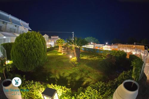 a yard with palm trees and a fence at night at La SkalaVista in Skala Kefalonias