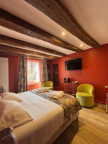 a bedroom with red walls and a bed with two chairs at Hotel De La Poste in Langres