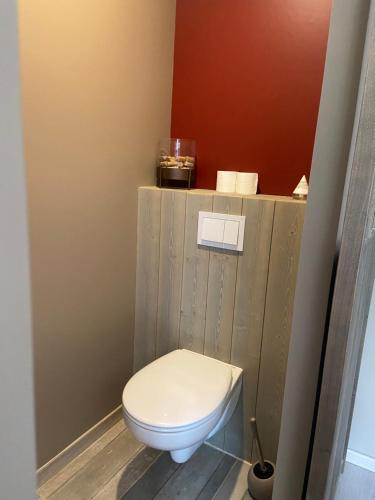 a bathroom with a toilet with a wooden wall at Chambres d hôtes La Bourneloise in Bournel