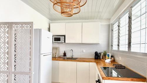 a kitchen with white cabinets and a white refrigerator at Le Maracuja - Jacuzzi privé à 2 min de la plage in Sainte-Anne