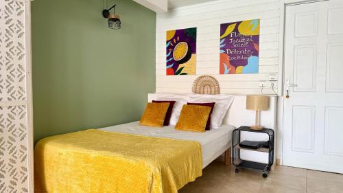 a bedroom with a bed with a yellow bedspread at Le Maracuja - Jacuzzi privé à 2 min de la plage in Sainte-Anne