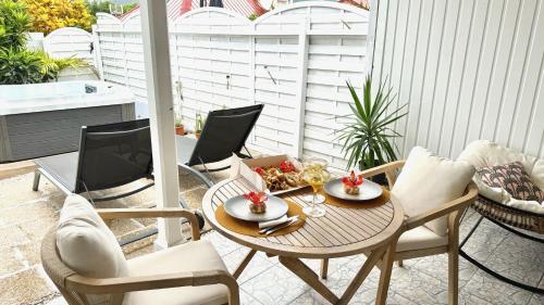 a patio with a table and chairs on a porch at Le Maracuja - Jacuzzi privé à 2 min de la plage in Sainte-Anne