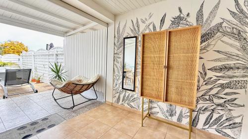 a room with a chair and a wall with a mural at Le Maracuja - Jacuzzi privé à 2 min de la plage in Sainte-Anne