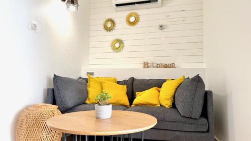 a living room with a gray couch with yellow pillows at Le Maracuja - Jacuzzi privé à 2 min de la plage in Sainte-Anne