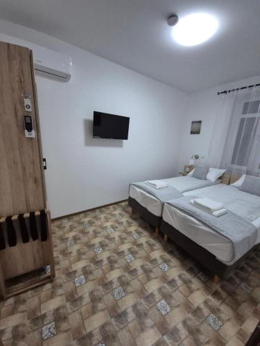 a bedroom with a bed and a flat screen tv at Altair Árpád Apartman in Vecsés