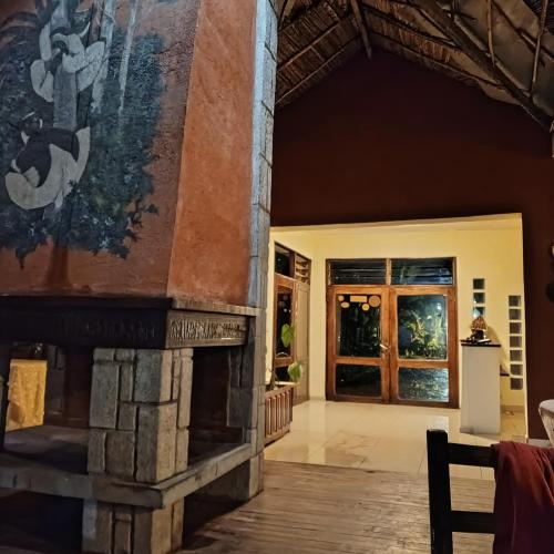 an open living room with a stone fireplace at Indri Lodge in Andasibe